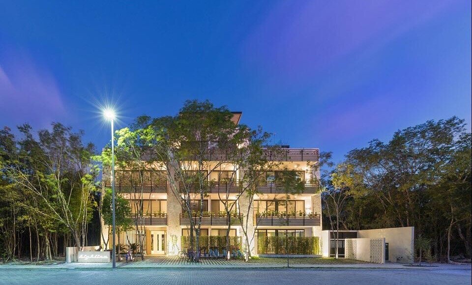 The Highline Tulum building at dusk on Calle Sayil, Aldea Zama - a boutique four-floor condominium among jungle trees